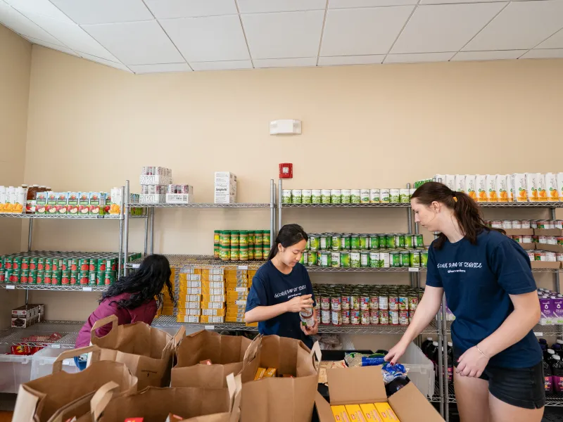 Students packing bags of canned goods from a food pantry.
