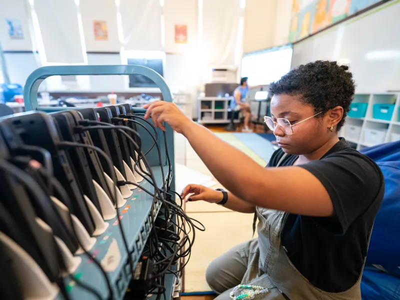 A young Black female fixes wires while working on a project.