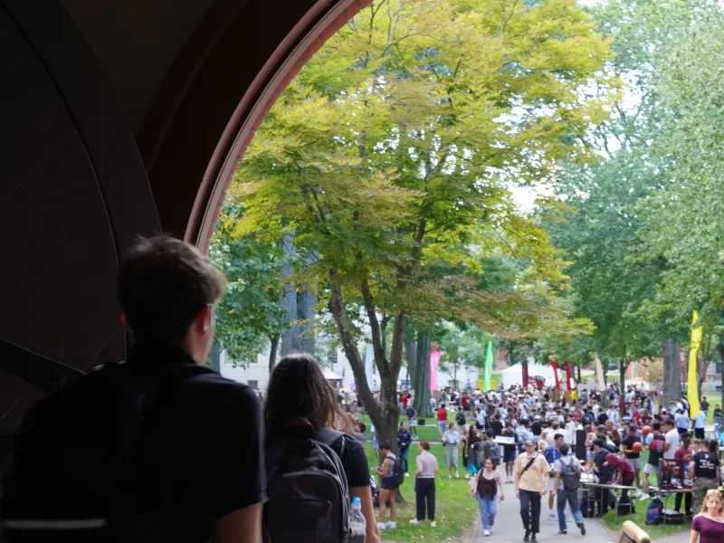 A color image of current students passing under the arches into Harvard Yard.
