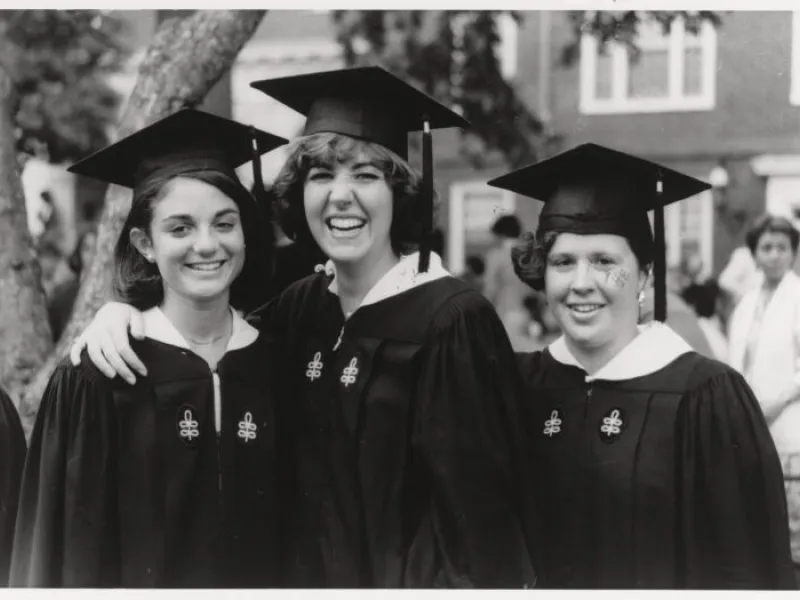 A black and white image of three females smiling together on Commencement day in 1986.