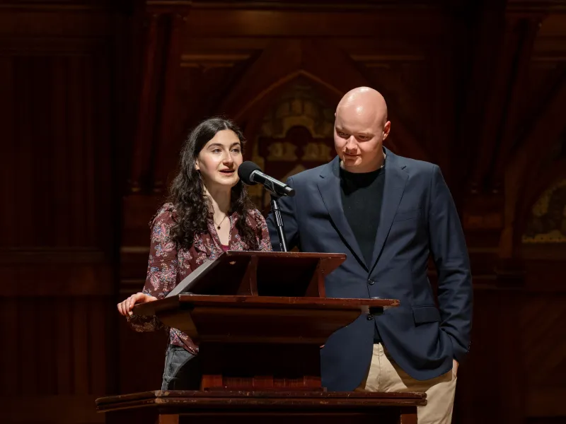 Student Ari Kohn '26 (left) speaking at a podium next to Jack Flanigan '27.