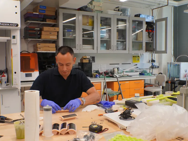 A man sitting alone working at a lab bench in 2026.