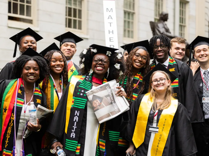 A colorful shot of a group of students smiling together in their regalia on Commencement day 2025.