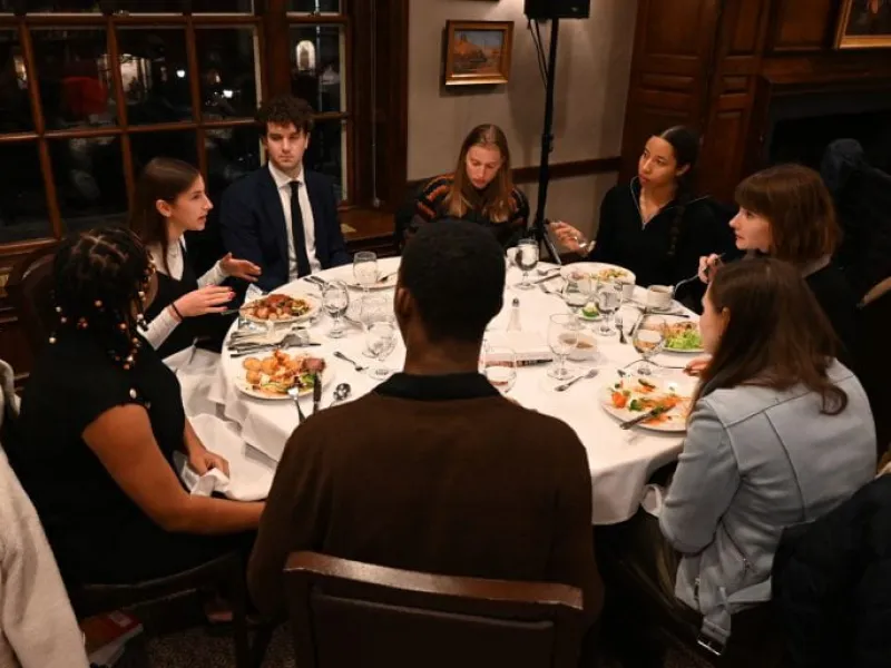 Student engaging in dialogue over a dinner table.