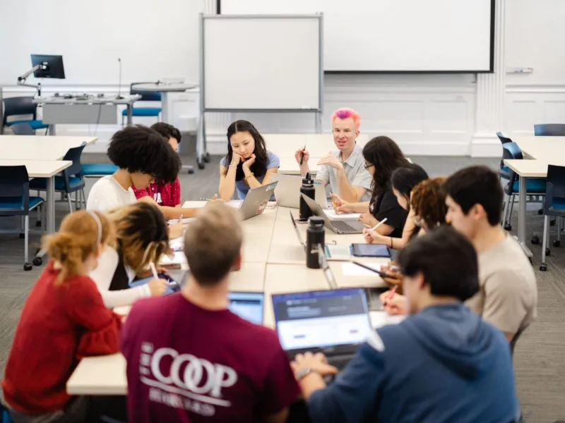A group of students sitting around a table together talking.