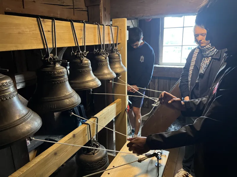 A male student pulling on small strings of bells.