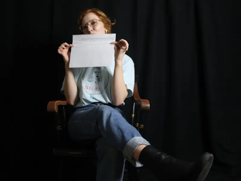 student in a chair and holding a piece of paper