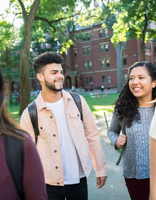 Four students smiling and walking through campus