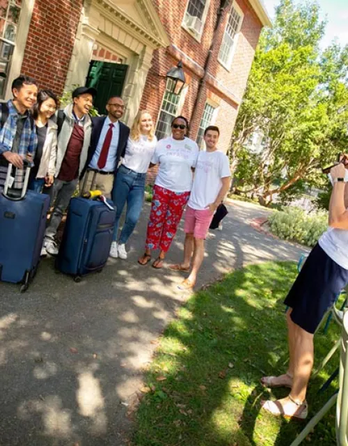 Dean of Students Katie O’Dair photographs newcomer David Zhang (center with hat) as he poses with Adele Fleet Bacow, Harvard President Larry Bacow, and Senior Assistant Dean of Residential Life and First-Year Students Nekesa Straker. 