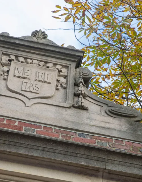 The Veritas shield engraved on one of the gates around Harvard Yard