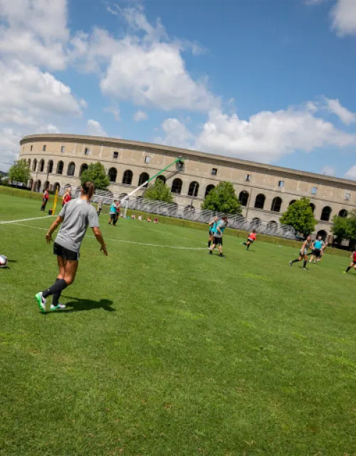 Members of the Harvard community playing soccer outside of Harvard Stadium.