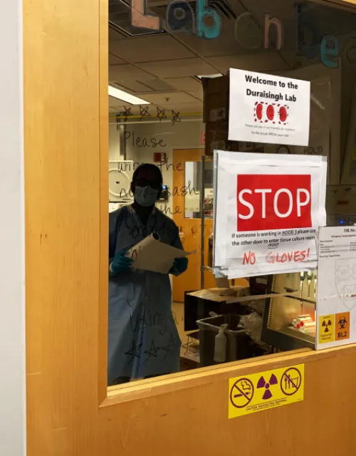 Research associate Aditya Paul works in the Duraisingh Lab, where signs illustrate new safety protocols.