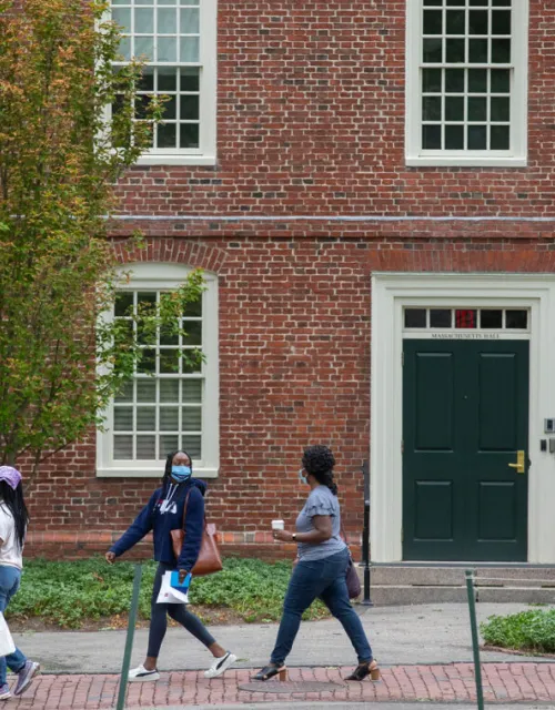 Lara Dada '24 (second from left) walks with her family past Massachusetts Hall.