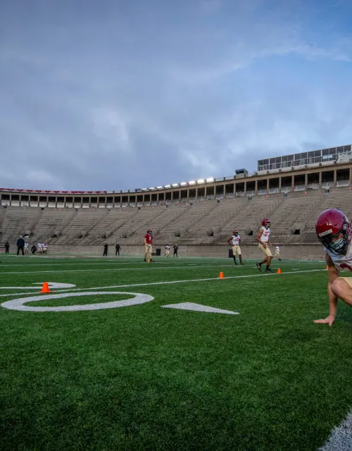 Defensive back Garrett Sharp '24 does an end-of-practice drill with his teammates at sunup in Harvard Stadium.