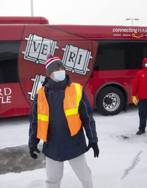 James Monahan (front), associate director of Transit & Fleet Management, and shuttle driver Densis Pena at the Bus Shop in Allston. Harvard will replace four biodiesel buses with 100 percent electric buses this fall.
