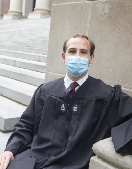 Jordan Bliss Perry '21, who will give the Latin Salutatory, sits on the Widener Library steps.