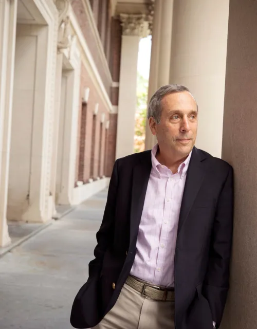 Larry Bacow poses against column at Widener Library 