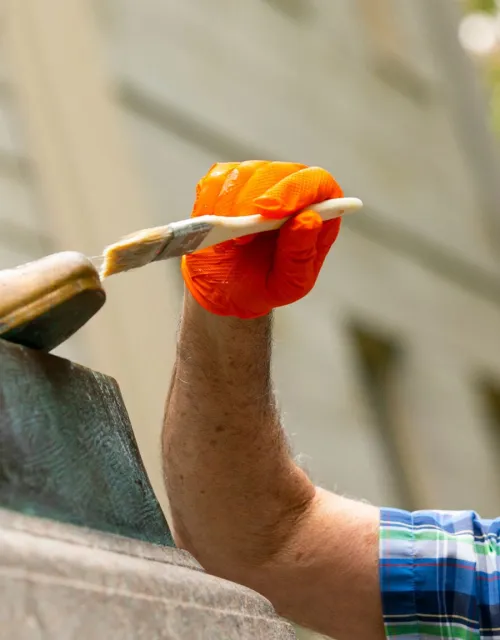 John Harvard's statue's foot being brushed during the renovation process