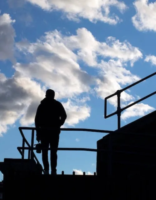 Student athlete stares out onto the football field on the stadium steps.