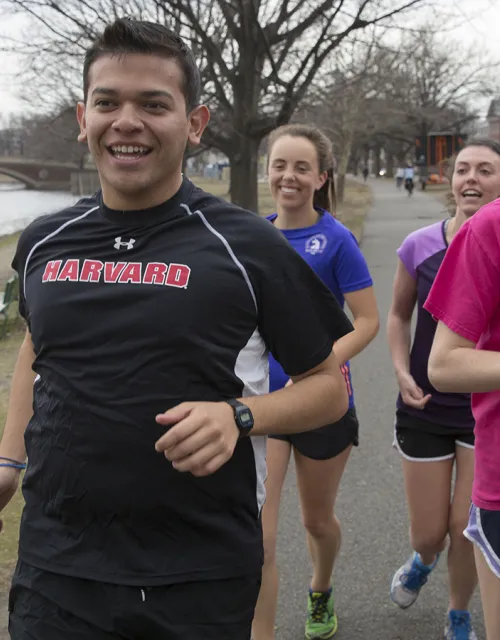 students running along the Charles River