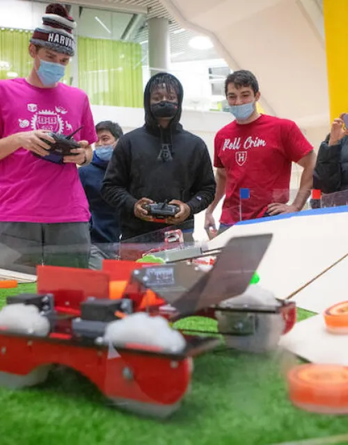 Bernard Zoungrana ('24), center, drives his robot during the finals of the Turf Wars robotics competition at the Science and Engineering Complex in Allston.