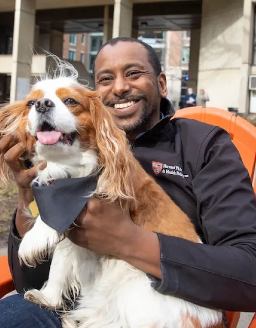 Anas El Turabi, a scholar in residence at Mather, holds his cavalier King Charles spaniel Cori, the House's informal mascot, greeter, and morale booster.