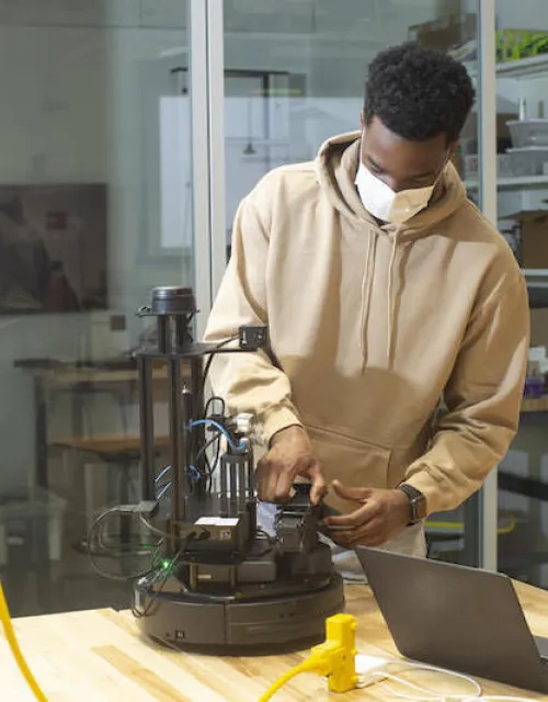 Second-year student Emeka Ezike adjusts his robot during a "CS286: Multi-Robot Systems – Control, Communication, and Security" mini-hack in the Science and Engineering Complex.
