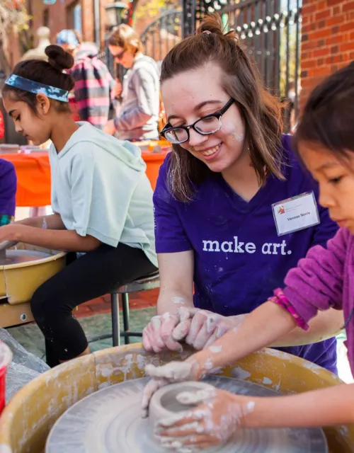 ARTS FIRST volunteer helping girl make pottery