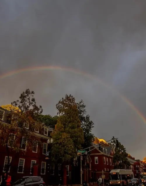 Landscape photo of Cambridge with a rainbow in the background.