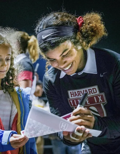 A student-athlete signs a fan's poster.