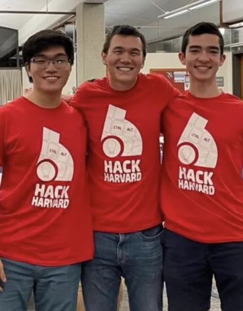 3 coders smiling and wearing shirts with the words, "Hack Harvard."