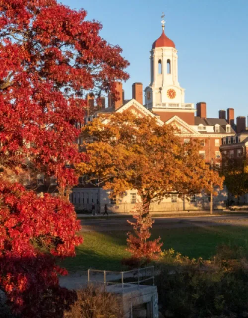 Photo of Dunster House from across the river with beautiful fall colored trees in the frontground. 
