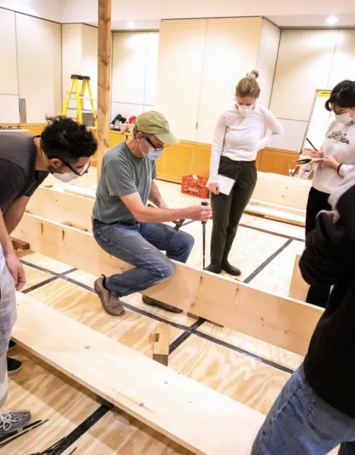 Students gather around instructor Douglas Brooks as they build a Japanese river skiff