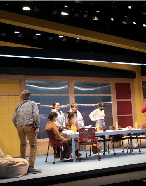 Actor sitting around a table onstage for "The Singularity Play"