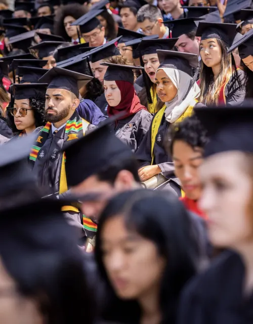 graduates in caps and gowns in seats on commencemnent