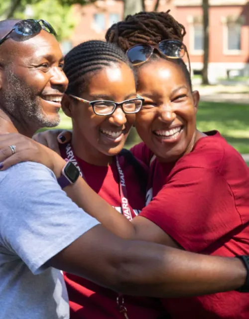 Lulu August ’26 (center) is hugged by her proud parents, Kakuri and Agnes, during first-year move-in last August in Harvard Yard. Photos by Kris Snibbe/Harvard Staff Photographer