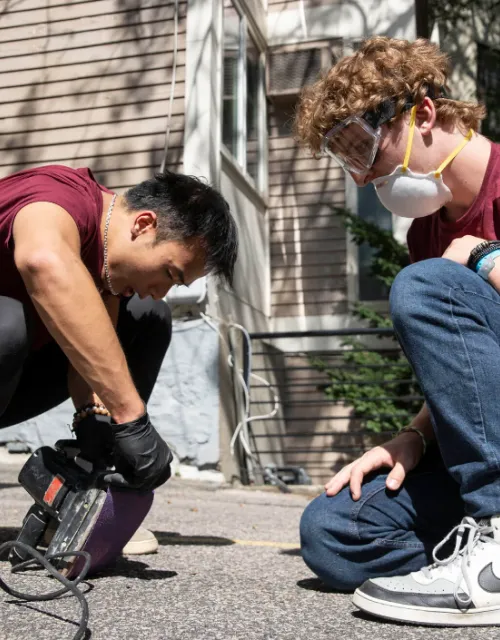 Xuanthe Nguyen ’25 (left) and Luke Blanchette ’27 prep the sander before they tackle fences at the historic Harriet Jacobs House in Cambridge.