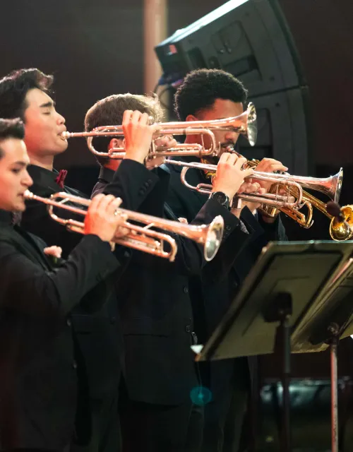 Students playing wind instruments on stage. 