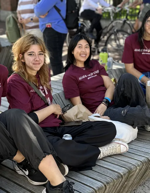 5 students taking a break during global day of service. they are sitting in science center plaza. all of them are wearing crimson shirts that say "global day of service"