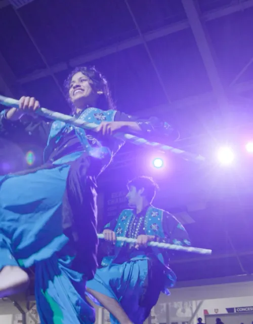 Students dance on stage in colorful garb