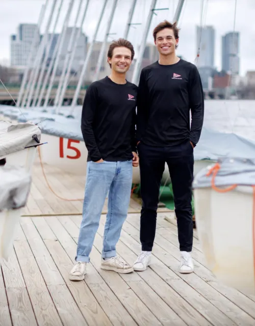 Justin (left) and Mitchell Callahan ’26 at the Harvard Sailing Center along the Charles River.