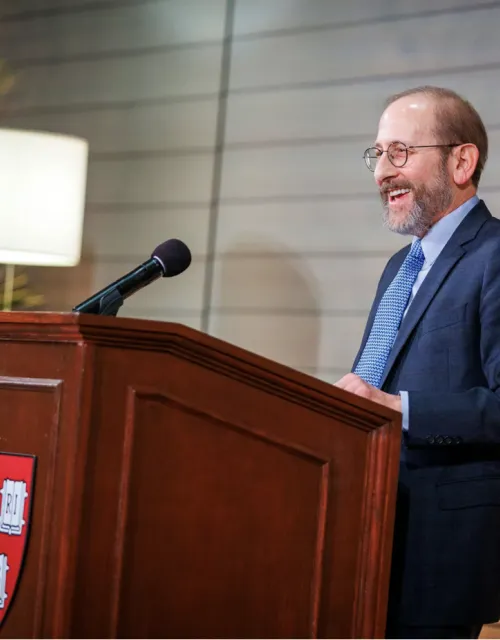 Alan Garber stands behind a podium with the Harvard Shield 