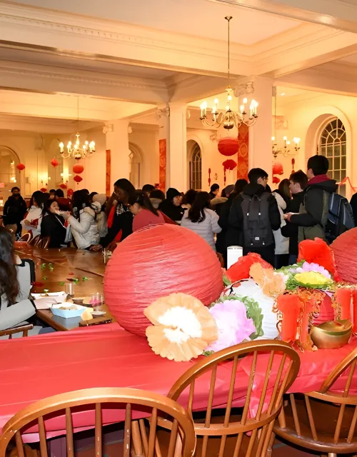 A crowded room decorated with red lanterns and festive decor, filled with people socializing around tables.