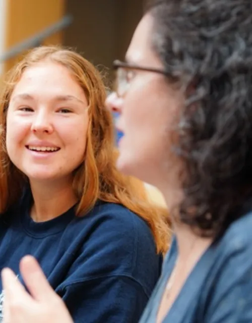 Two people sitting at a table in a dining area, engaged in conversation.