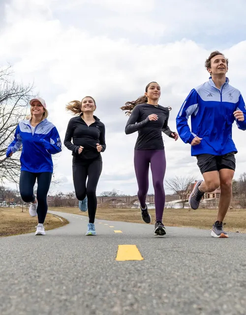 Four people jogging on a paved path outdoors.