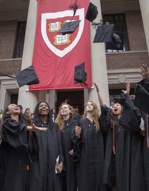 Graduates in gowns celebrate by tossing caps in the air