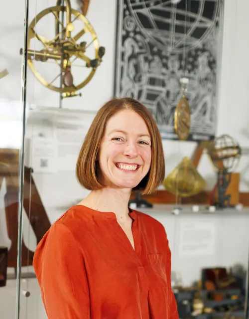 Hannah Marcus smiles in a bright red top at the Collection of Historical Scientific Instruments. 