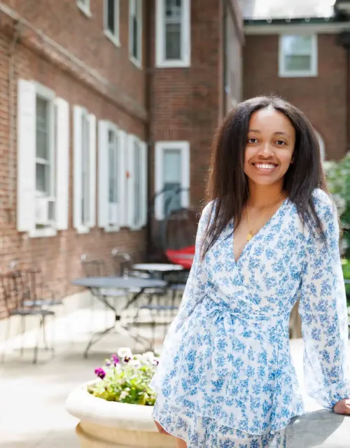 Sophia Scott, Class of 2025, smiles and poses in a white and blue dress at Harvard College.