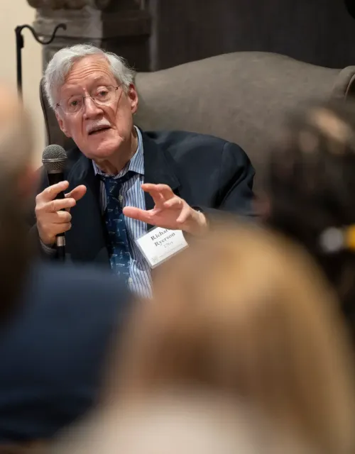 Historian Dick Ryerson sitting and speaking to a sitting crowd