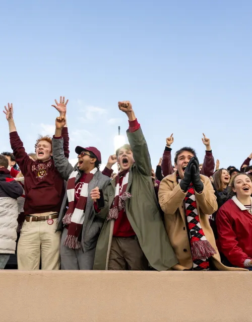 A line of Harvard College students cheer empatically in the front row at the Harvard-Yale game.